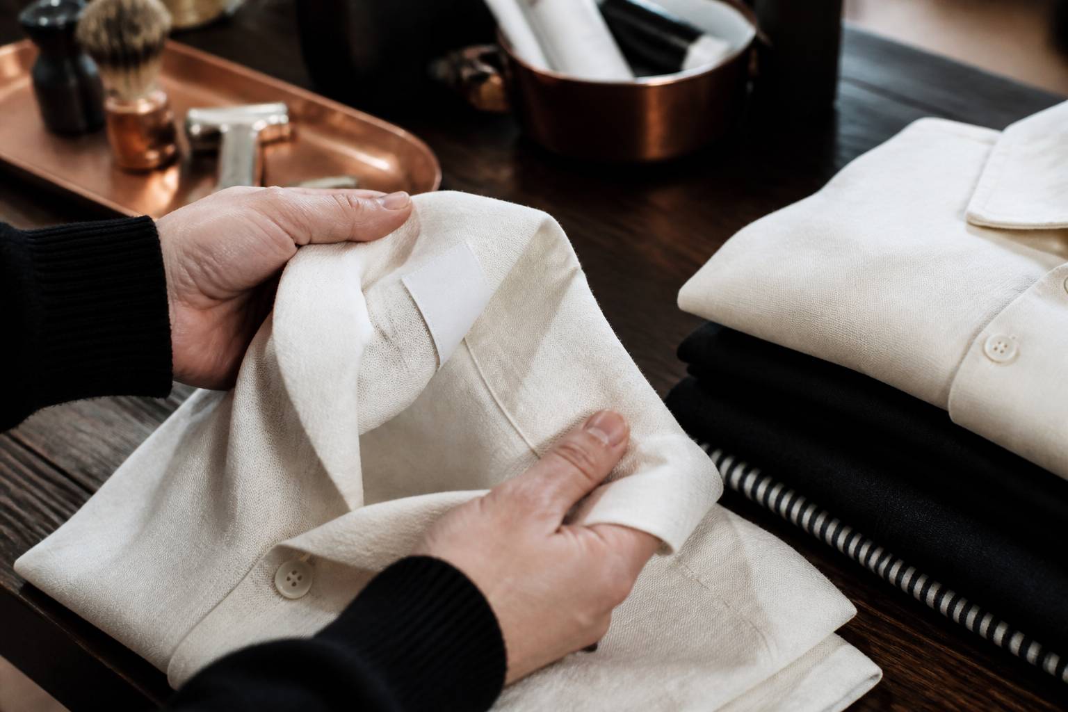 Mains examinant la couture et le tissu d'un vêtement en lin plié